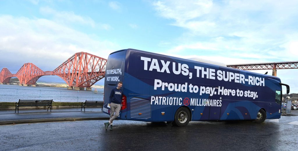 Patriotic Millionaires UK campaign coach wrapped by Transit Media parked beside the Forth Bridge in Scotland