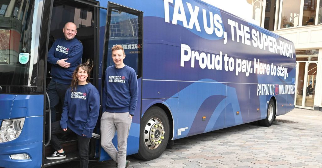 Patriotic Millionaires UK team standing beside fully wrapped campaign coach designed by Transit Media