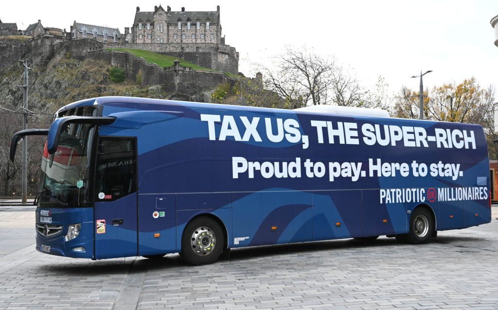 Transit Media full coach wrap for Patriotic Millionaires UK displayed near Edinburgh Castle during nationwide tour